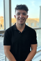 Joseph wearing a stripped blue shirt smiling at camera.