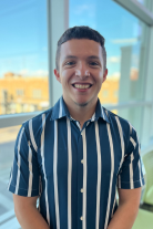 Joseph wearing a stripped blue shirt smiling at camera.