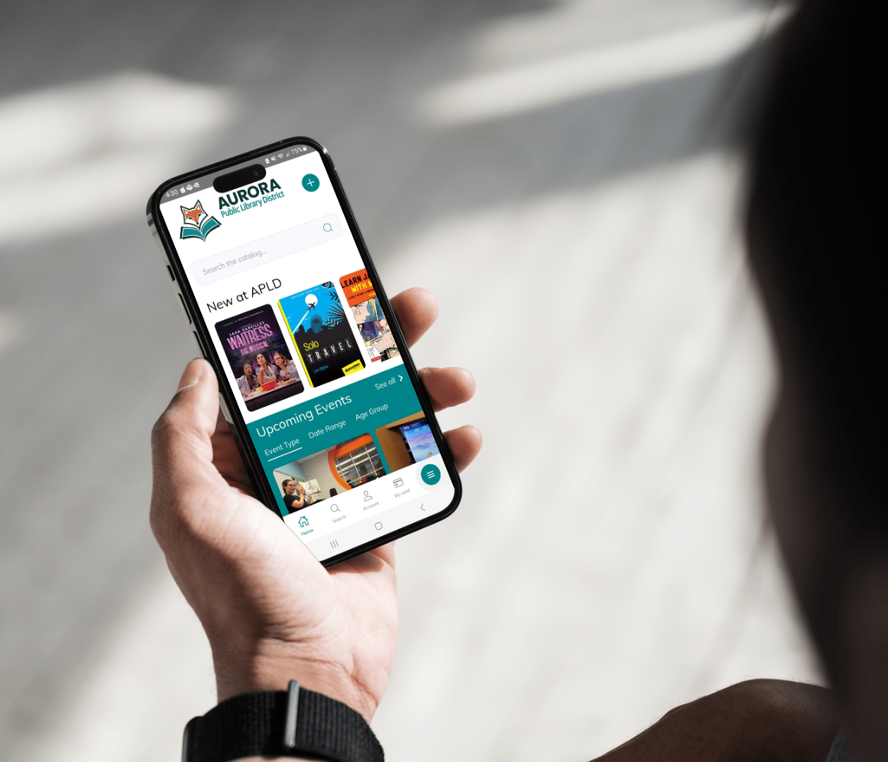 Closeup of a person holding their phone displaying the APLD app home screen.