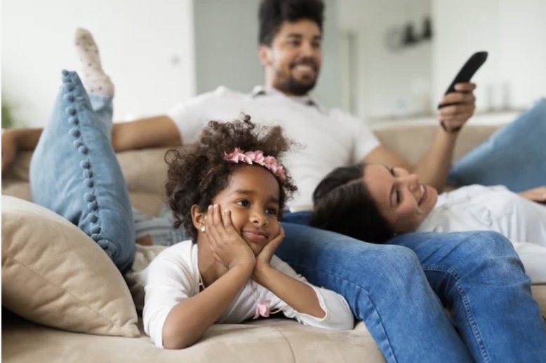 Family lounges on the couch watching TV