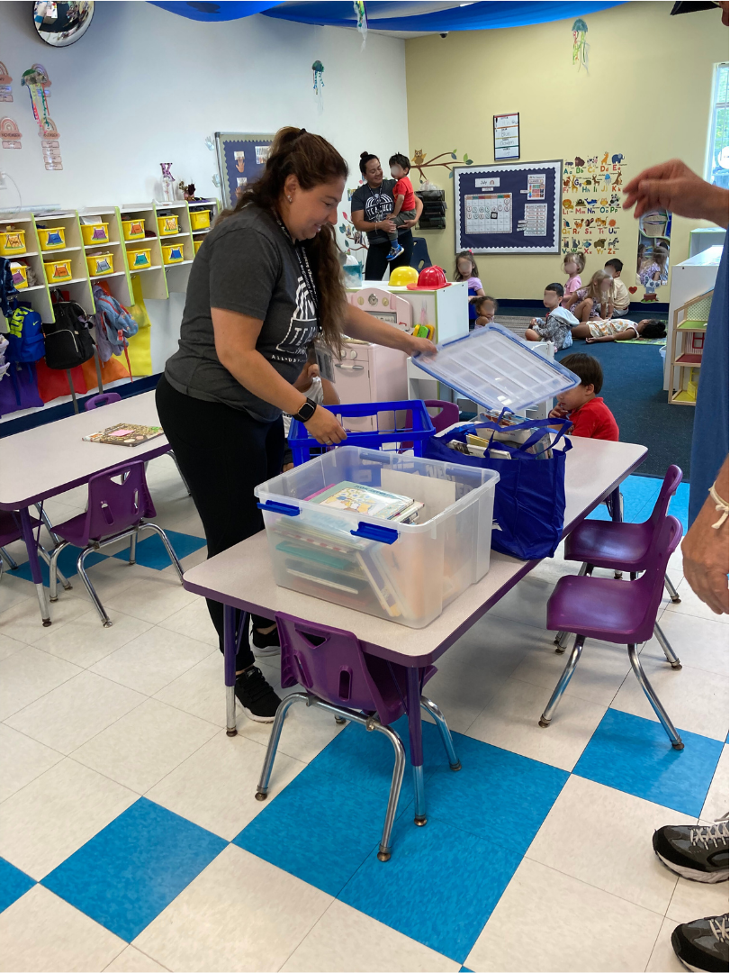 Daycare teacher unloads items from a library delivery.