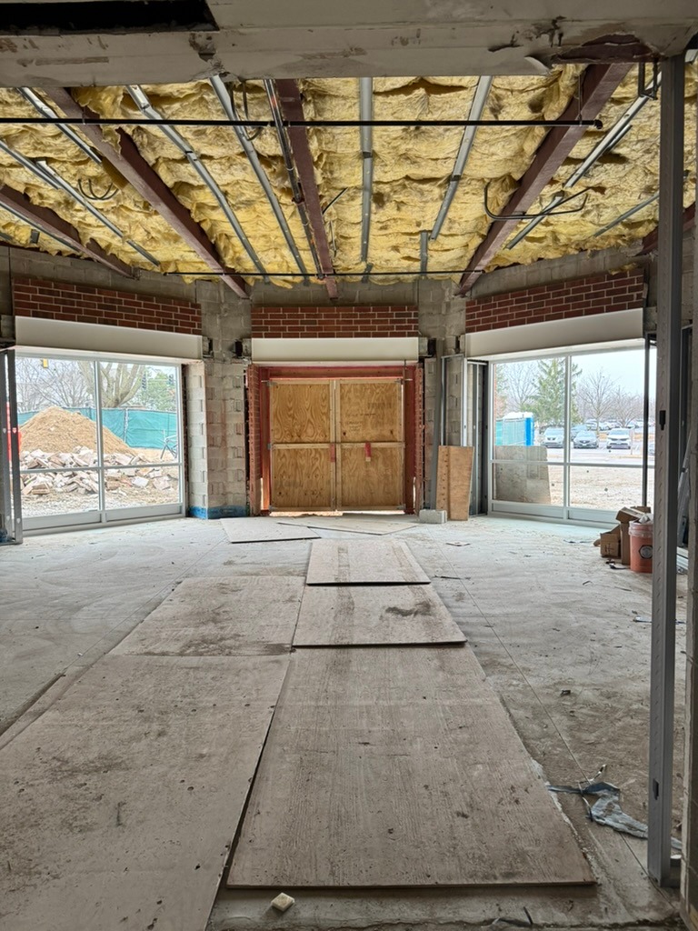Boarded up front entry doors with large windows on either side.